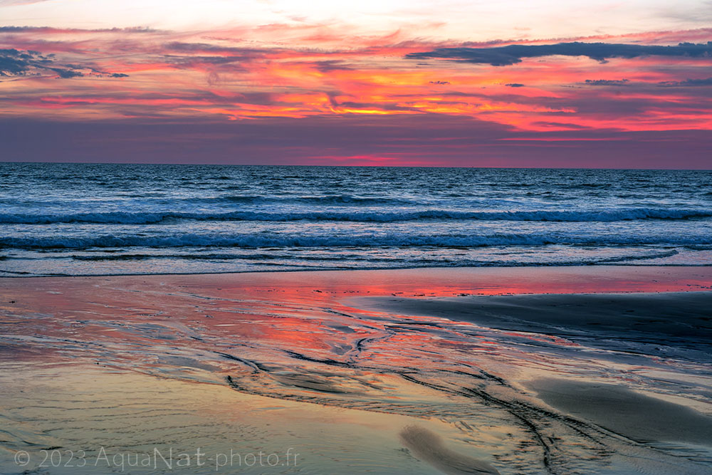 ciel rouge et reflet du ciel dans le sable mouillé de l'estran